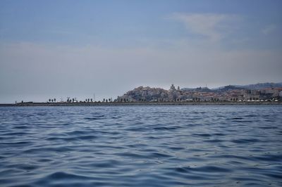 Scenic view of sea by buildings against sky