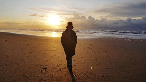 Man standing on beach against sky during sunset