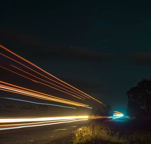 Light trails on road against sky at night