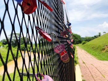 Close-up of love locks on fence against sky