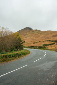 Road amidst field against sky