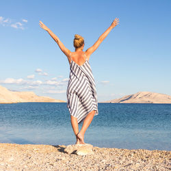 Full length of woman standing at beach against sky