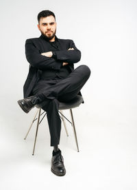 Young man sitting on chair against white background