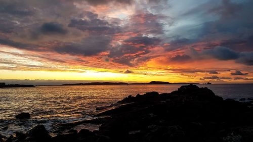 Scenic view of sea against dramatic sky during sunset