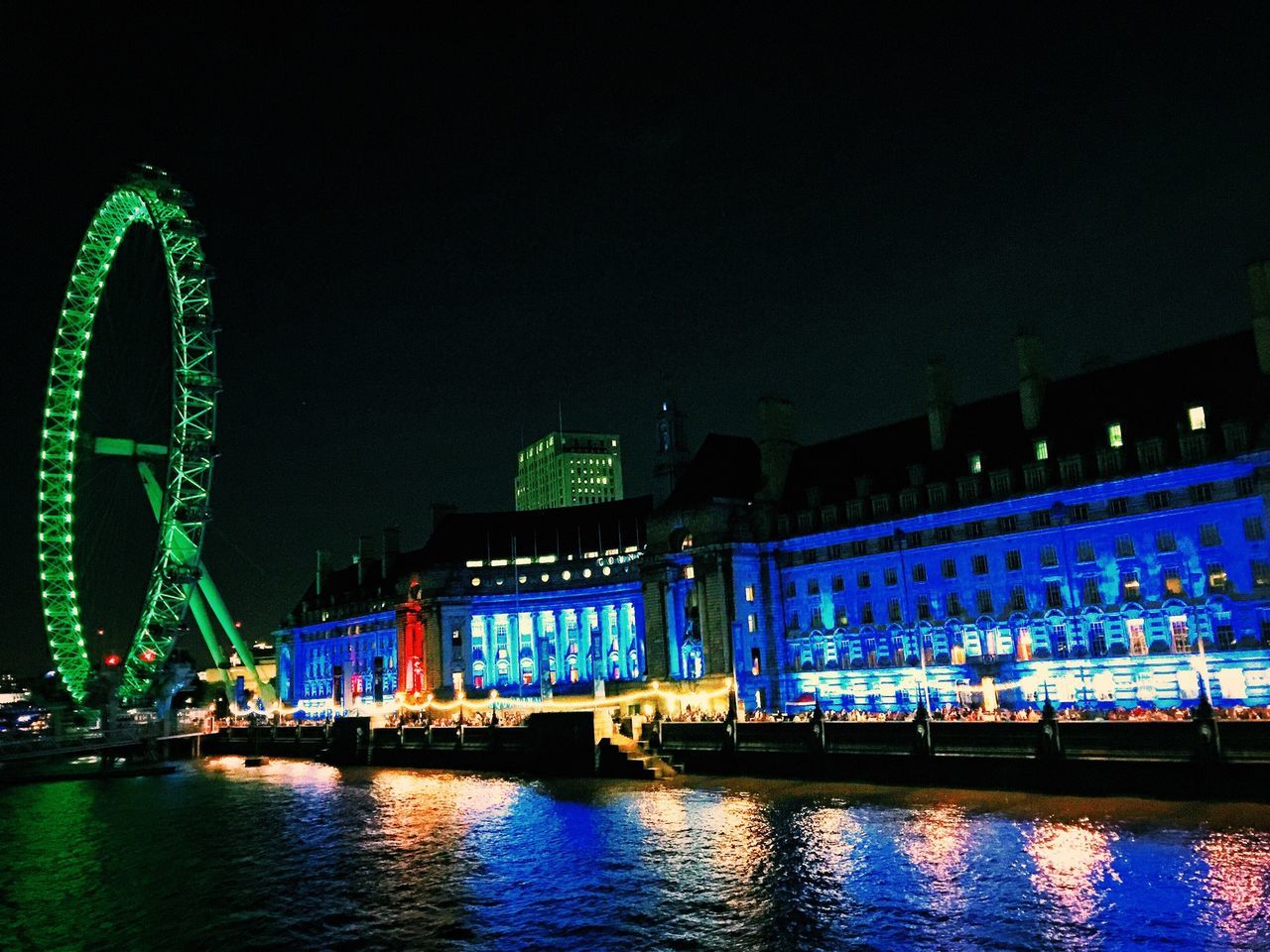 night, illuminated, architecture, built structure, water, building exterior, waterfront, ferris wheel, city, clear sky, blue, reflection, arts culture and entertainment, river, transportation, travel destinations, sky, travel, outdoors, incidental people