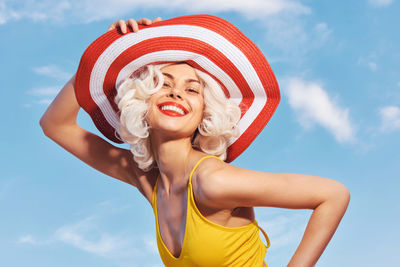 Low angle view of woman wearing hat against sky