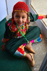 High angle portrait of girl in traditional clothing sitting at home