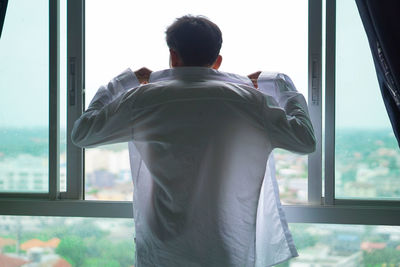 Rear view of a man looking through window