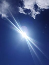 Low angle view of sun shining in blue sky