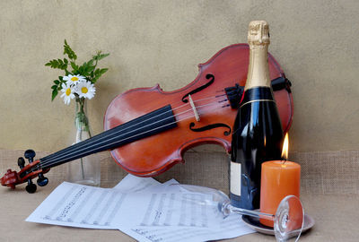 Close-up of violin with wine bottle and candle on table