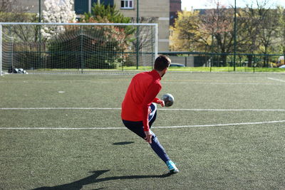 Rear view of man playing soccer on field