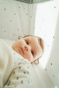 Directly above shot of cute baby girl lying on bed at home