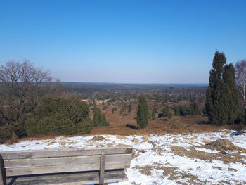 Scenic view of field against clear blue sky during winter