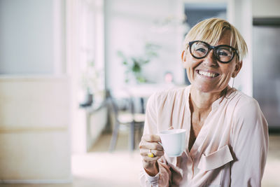 Portrait of smiling woman drinking coffee at home