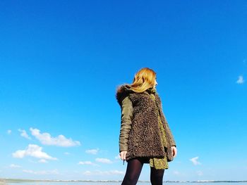 Rear view of woman standing against blue sky