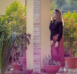 Woman standing by potted plants in yard