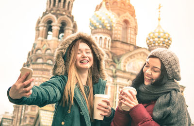 Portrait of smiling young woman using smart phone in city