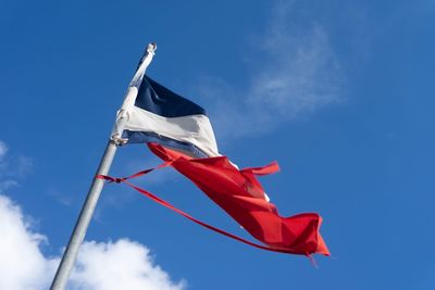 Low angle view of flag against blue sky