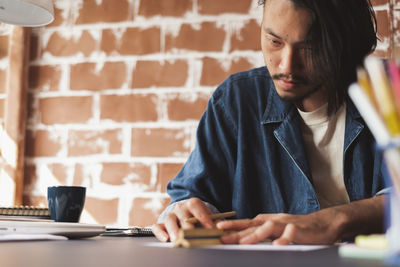 Midsection of man using mobile phone while sitting on table