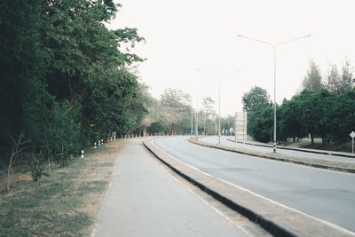 Road by trees against sky