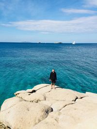 Rear view of man standing at beach against sky