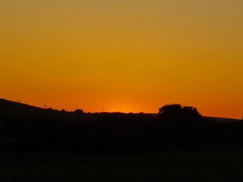 Scenic view of silhouette landscape against orange sky