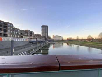 River by buildings against sky during sunset