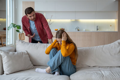 Side view of woman using mobile phone while sitting on bed at home