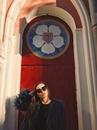 Portrait of woman wearing sunglasses against church 