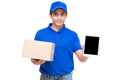 Portrait of salesman holding cardboard box and digital tablet while standing against white background