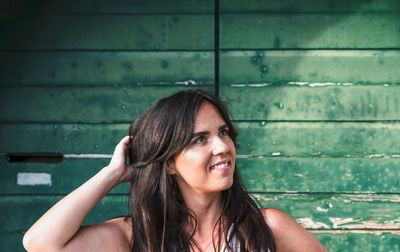 Portrait of a beautiful young woman against green wooden backdrop. hair, hairstyle, attractive, face