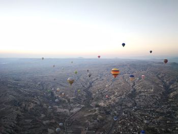 Hot air balloons flying over landscape against sky