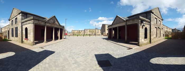 Street amidst buildings against sky on sunny day