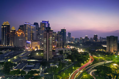 High angle view of illuminated street amidst buildings at night