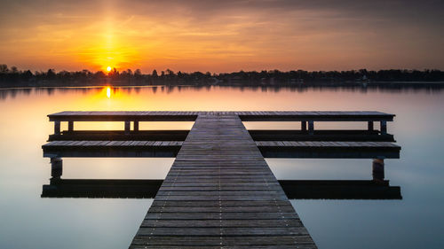 Pier over lake against sky during sunset