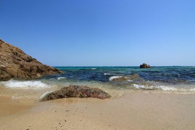 Scenic view of beach against clear blue sky