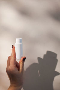 A tube of face and body care cosmetics in a woman's hand with hard shadows 