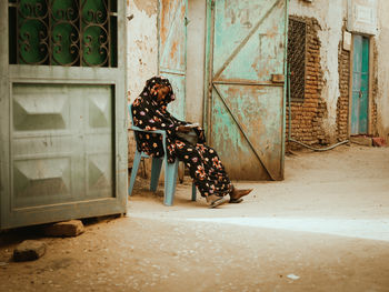 Side view of woman sitting in abandoned house