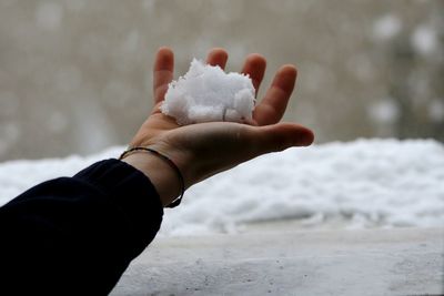 Cropped hand of child holding snow outdoors