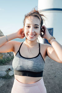 Portrait of young woman standing against wall