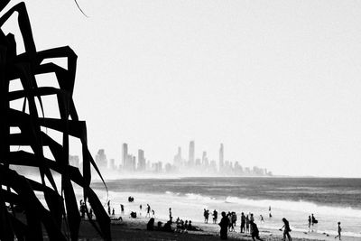Silhouette people at beach against clear sky