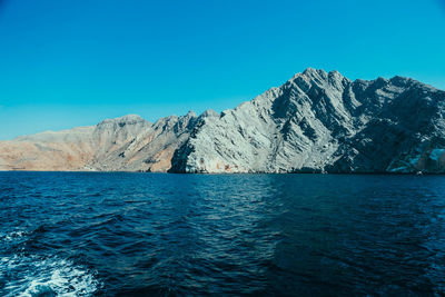 Scenic view of sea and mountains against clear blue sky