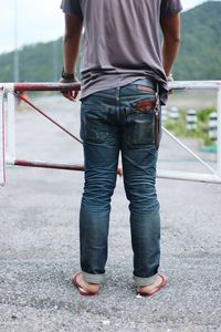 Low section of man standing on railing