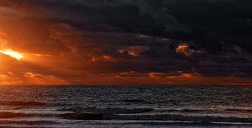 Scenic view of sea against dramatic sky during sunset