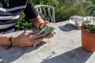 Midsection of man using mobile phone at table