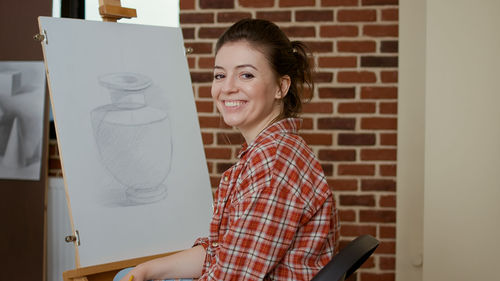 Portrait of young woman using mobile phone while standing at home