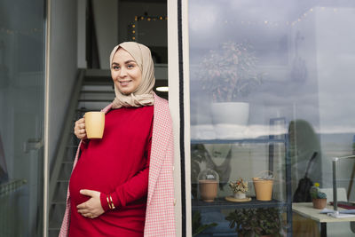 Thoughtful woman with coffee cup at doorway