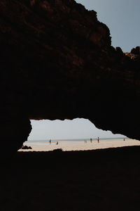 Silhouette rock formation on beach against sky