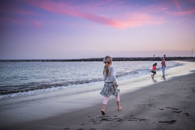 Rear view of people at beach against sky