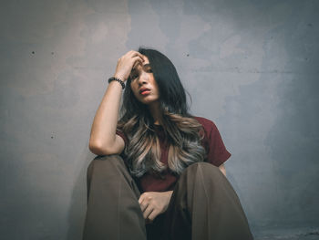 Portrait of beautiful young woman standing against wall